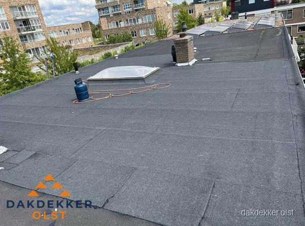 Bitumen dakbedekking op plat dak met lichtkoepel en schoorsteen in Olst