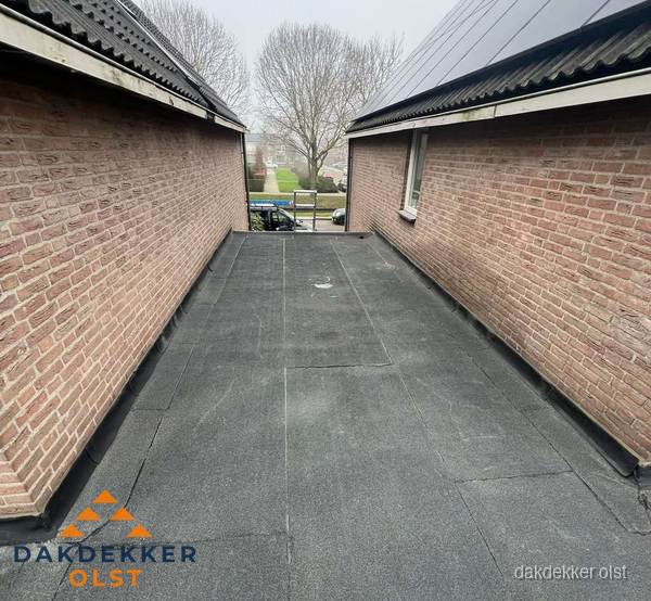 Plat dak met bitumen dakbedekking tussen bakstenen muren in Olst Plat dak met bitumen dakbedekking tussen bakstenen muren in Olst
