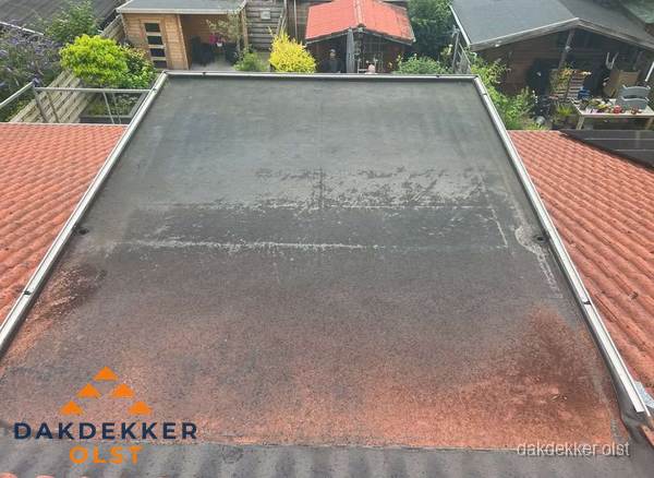 Verouderd plat dak met slijtage tussen schuine daken in Olst Verouderd plat dak met slijtage tussen schuine daken in Olst